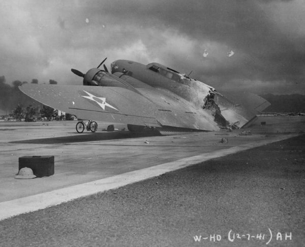 A burned B-17C aircraft rests near Hangar Number Five, Hickam Field, following the attack by Japanese aircraft. Pearl Harbor, Hawaii. Photo by anonymous (7 December 1941). Department of Defense. PD-USGOV. National Archives and Records Administration and Wikimedia Commons.