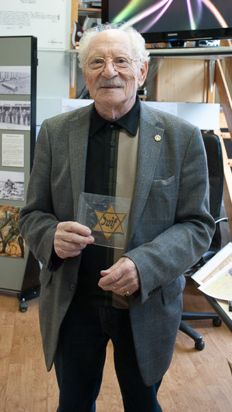 Lucien Tinandar holding the Star of David patch that belonged to and worn by his mother during the Occupation. Photo by Sandy Ross.