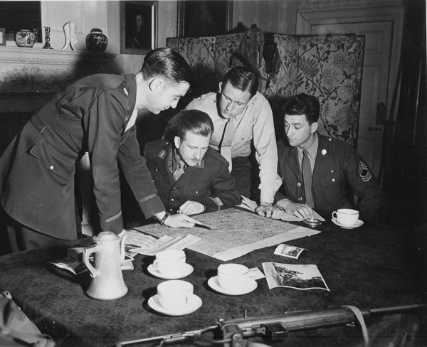 Jedburghs get instructions from briefing officer in London. Photo by anonymous (c. 1943−1944). U.S. National Archives and Records Administration. PD-Free License. Wikimedia Commons. 