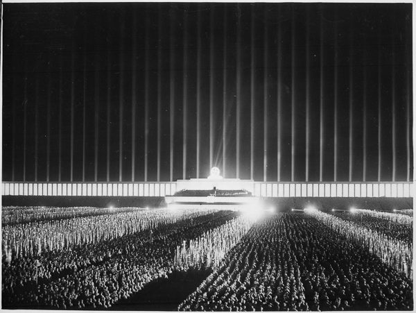 Assemblage of political leaders on the searchlight-illuminated Zeppelin field in Nuremberg. Photo by anonymous (September 1937). U.S. National Archives and Records Administration. PD-USGovernment. Wikimedia Commons. 
