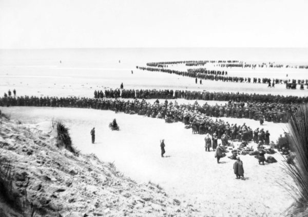British troops line up on the beach at Dunkirk to await evacuation. Photo by anonymous (c. May 1940). American Embassy Second World War Photograph Library-Classified Print Collection. PD-United Kingdom Government. Wikimedia Commons. 