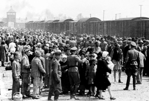 “Selection” process of Hungarian Jews on the ramp at Auschwitz II-Birkenau. The majority of the men, women, and children would be dead within hours. Notice the entrance building in the background (left). Photo by likely either Ernst Hoffmann or Bernhard Walter of the SS (c. May/June 1944). Yad Vashem – The Auschwitz Album. PD-Expired copyright and author is anonymous. Wikimedia Commons. 