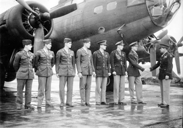 Colonel Curtis LeMay officially congratulates a bomber crew of the 306th Bomb Group. Their B-17 was shot down after a raid on Germany after destroying eleven Fw 109s and were rescued from the sea after thirty hours on the water. Photo by anonymous (2 June 1943). Imperial War Museum. PD-USGOV. Wikimedia Commons. 