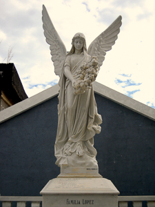 Sculpture of an angel holding floral bouquet. Sculpture by anonymous (date unknown). Photo by Ramiltibayan (2015). Balayan, Batangas Cemetery. PD-CCA-Share Alike 4.0 International. Wikimedia Commons. 