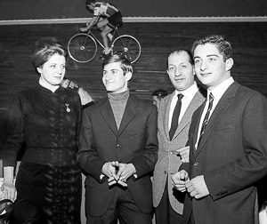 Italian racing cyclist Gino Bartali (center right) posing with his wife Adriana Bani (left) and their sons Andrea (right) and Luigi (center left) during a track cycling race. Photo by Angelo Cozzi (c. 1960). PD-Expired Copyright. Wikimedia Commons. 