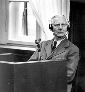 Hjalmar Schacht testifying at the Flick Trial. He confirmed Flick had contributed to the Nazi Party’s campaign fund in 1933 after Hitler promised to protect private industry and eliminate all strikes. Photo by anonymous (c. 1947). PD-U.S. Government. Wikimedia Commons. 