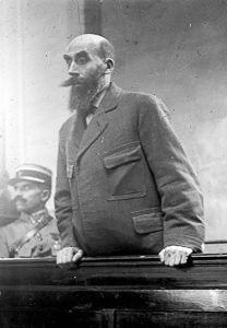 Landru in the dock at his trial. Photo by anonymous (c. November 1921). PD-Author’s Life plus 70-years or less. Wikimedia Commons. 