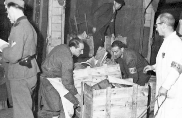 Prisoners unloading crates of stolen personal property. German soldiers on the left are supervising. Photo by anonymous (c. 1943). German Federal Archives, Koblenz.
