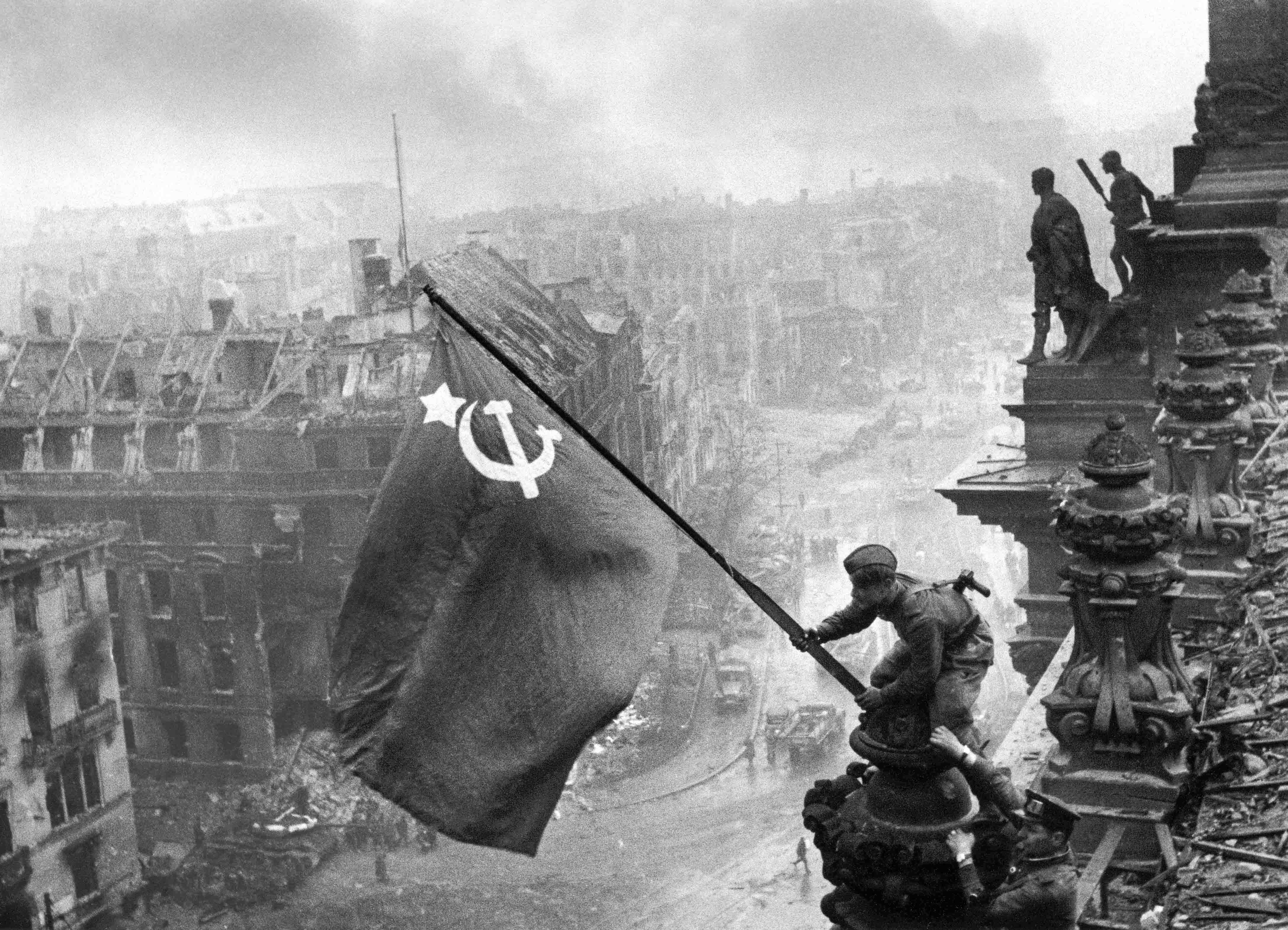 Soviet flag raised on the Reichstag during the Battle of Berlin. Photo by Yevgeny Khaldei (2 May 1945). Ministry of Defense of the Russian Federation (Mil.ru). PD-Author release. Wikimedia Commons.