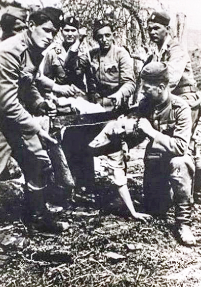 Ustaša militia sawing off Branko Jungić’s head. Jungić was a Serb living in the village of Grabovac. Photo by anonymous (c. 1941 to 1945). PD-Public domain of country of origin. Wikimedia Commons.