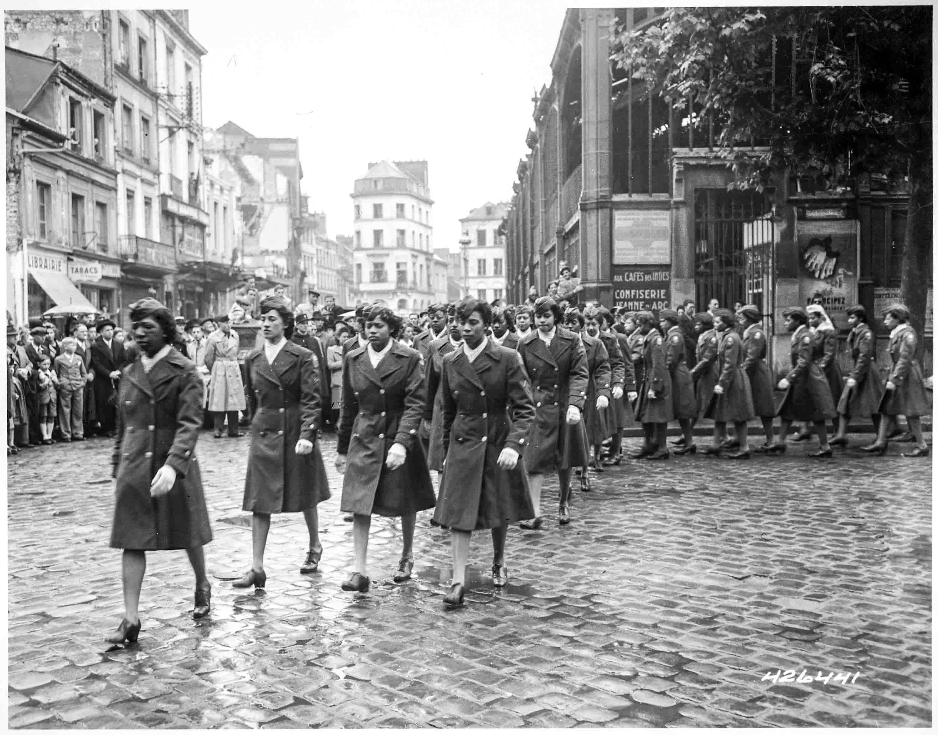 Members of the 6888th participate in a victory parade on 27 May 1945 in Rouen, France, passing through the market place where Joan of Arc was executed. Photo by anonymous (27 May 1945). National Archives and Records Administration. PD-U.S. Government. Wikimedia Commons.
