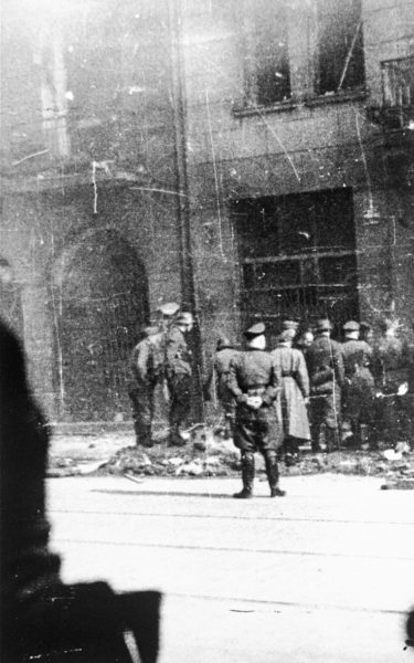 German police and SS personnel arrest Jews on Nowolipie Street in the Warsaw Ghetto during the suppression of the uprising. Photo by Leszek Grzywaczewski (c. April/May 1943). U.S. Holocaust Memorial Museum, courtesy of Howard Kaplan.