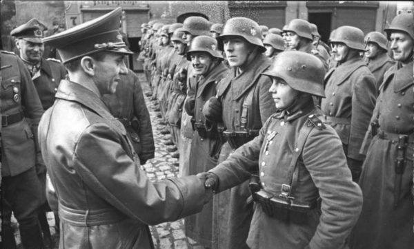 Joseph Goebbels shaking hands with sixteen-year-old Willi Hübner. Photo by anonymous (9 March 1945). Bundesarchiv, Bild 183-J31305/CC-BY-SA 3.0. PD-CCA-Share Alike 3.0 Germany. Wikimedia Commons.