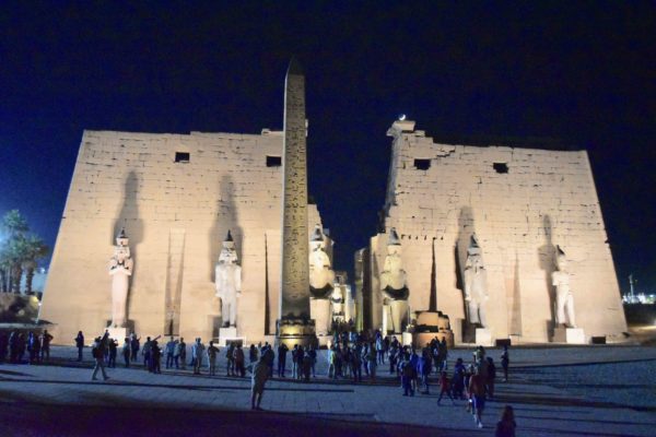 Entrance to Luxor Temple with obelisk on the left and statue of seated Ramses II guarding the entrance. Photo by Sandy Ross (2019).