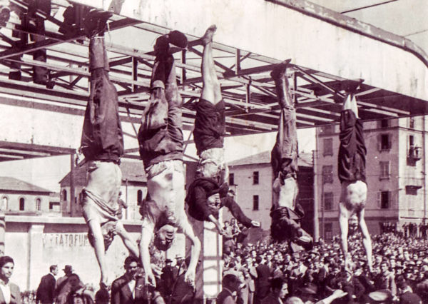 Mussolini’s dead body (second from left), his mistress, Claretta Petacci (third from left) and others hanging in Piazzale Loreto. Photo by Vincenzo Carrese (29 April 1945). PD-Published prior to 1 March 1989 without copyright notice. Wikimedia Commons.