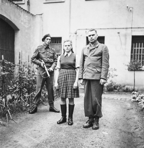 The liberation of KZ Bergen-Belsen. Irma Grese (center) standing in the courtyard of the prisoner of war cage at Celle with former camp commandant, Josef Kramer (right). Both were convicted of war crimes and sentenced to death. Photo by Sgt. Silverside (c. 1945). Imperial War Museum; War Office Second World War Official Collection. PD-U.K. Public Domain. Wikimedia Commons.