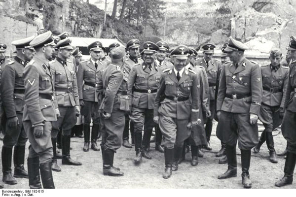 Heinrich Himmler (center right) with Nazi officers at KZ Mauthausen. Oswald Pohl, smiling at the SS guard, is to Himmler’s left. Photo by anonymous (27 April 1941). Bundesarchiv, Bild 192-015/CC-BY-SA 3.0. PD-CCA-Share Alike 3.0 Germany. Wikimedia Commons.