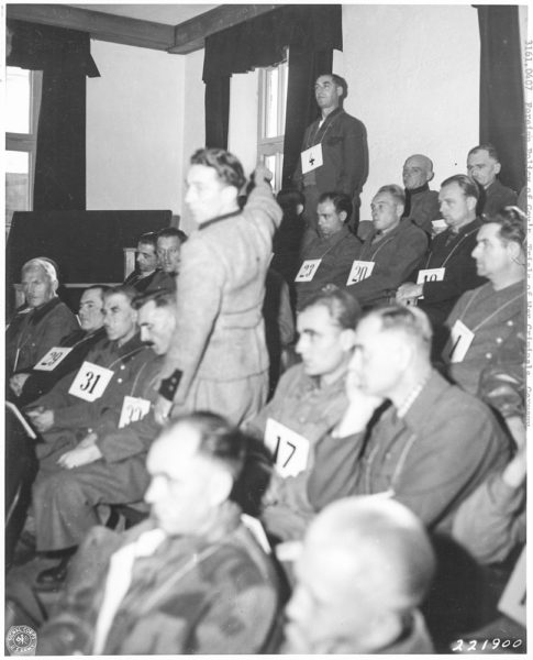 Dachau war crimes trial. Witness, Rudolf Wolf, points to Franz Trenkle (#4) as one of the forty accused torturers from KZ Dachau. Photo by anonymous (c. 1945/46). National Archives and Records Administration, Kansas City. PD-U.S. Government. Wikimedia Commons. 