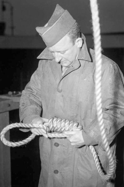 MSgt. John C. Woods, U.S. Army executioner, examining hanging rope. Photo by anonymous (date unknown).