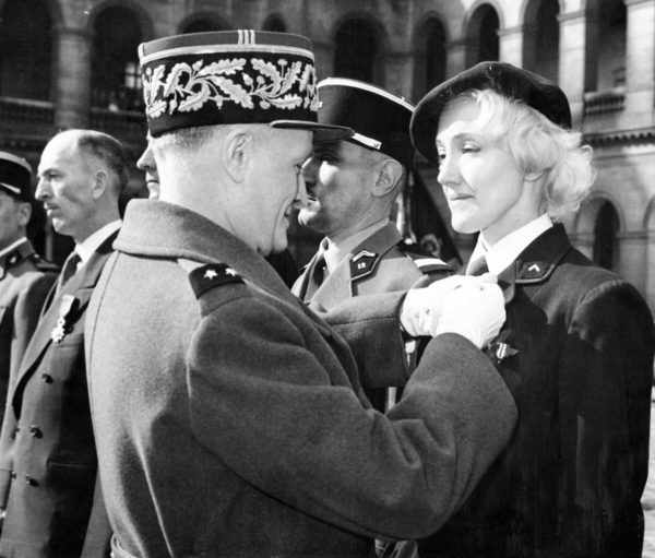 In the courtyard of the Invalides, Gen. Henri Masson pins the Legion of Honor on Lydia Lova, a dancer in Paris’ famous “Folies Bergère.” Photo by AP News-Features Photo. (c. March 1960). Author’s collection.