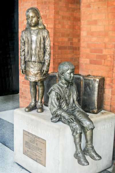 One of three statues standing inside Liverpool Street Station in the city of London. It commemorates the Kindertransports that linked Prague with London. Photo by Loco Steve. Statue by Flor Kent (November 2015). PD-CCA-Share Alike 2.0 Generic. Wikimedia Commons.