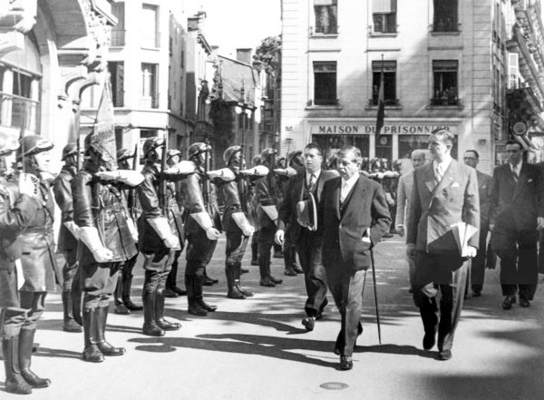 Vichy prime minister Pierre Laval (center right⏤white tie) and Vichy police chief René Bousquet (far right⏤carrying files) inspecting the Vichy Guard of Honor. Photo by anonymous (c. 1943). PD-Expired copyright. Wikimedia Commons. 
