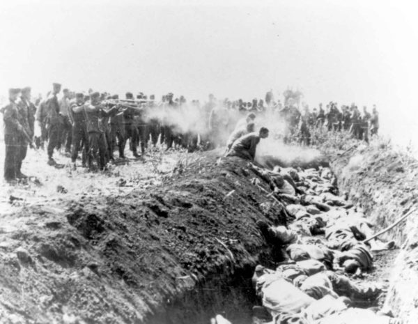 Men with an Einsatzgruppe execute a group of Soviet civilians kneeling by the side of a mass grave. Photo by anonymous (c. 1941). PD-Expired copyright. Wikimedia Commons.
