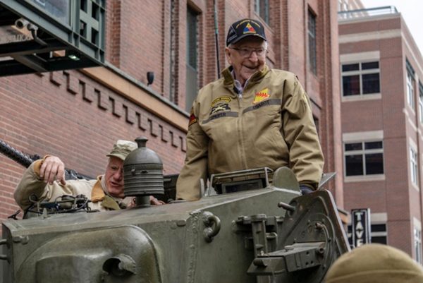 Former Cpl. Clarence Smoyer settles into a tank as volunteer historical re-enactors roll through lower downtown Denver. Smoyer served under MG Maurice Rose in World War II. Photo by Eric Lubbers (30 March 2019). The Colorado Sun via AP. https://www.youtube.com/watch?v=P3PdzviKqDQ