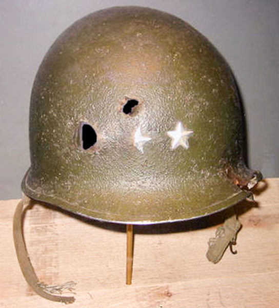Helmet worn by MG Maurice Rose when he was shot and killed on 30 March 1945. The bullets that struck Gen. Rose’s helmet did not kill him. The helmet flew off his head before he was struck by the third (of four) bursts from a 9mm “Schmeisser” automatic pistol. The first burst hit the general in the right cheek and knocked the helmet off his head. Photo by Jim MacClay (c. 2003). The Museum of Jewish Heritage, NYC.