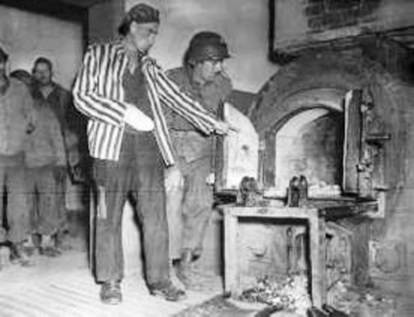 Former KZ Dora-Mittelbaum prisoner showing 3rd Armor Division soldier the camp’s crematorium. Photo by U.S. Signal Corps (c. April 1945). PD-U.S. Government. Wikimedia Commons.