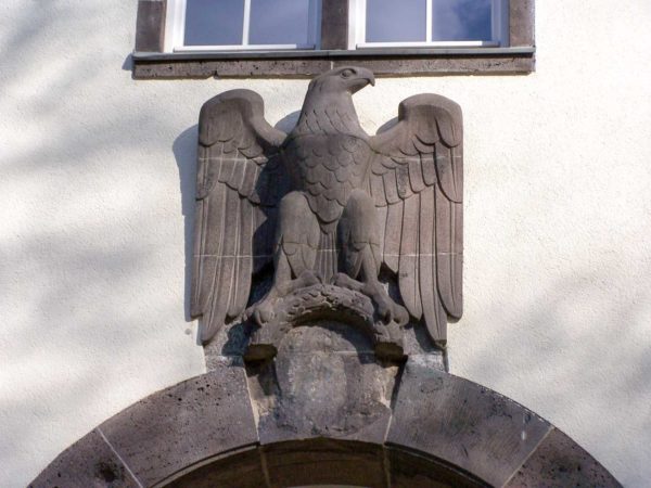 Eagle above the rear main entry to the Robert-Pioty building, University of Darmstadt. As part of the denazification process, the swastika has been removed under the eagle. Photo by S. Kasten (3 July 2006). PD-CCA-Share Alike 3.0 Unported. Wikimedia Commons. 