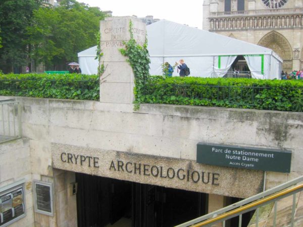 The entrance to the Crypte archeologioue, or Archeological Crypt. Notre-Dame is in the background. Photo by Geneticcuckoo (c. 2012). PD-CCA-Share Alike 3.0 Unported. Wikimedia Commons.