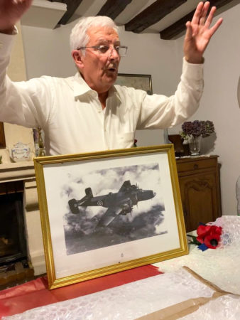 Jean-Pierre Curato opening his present from Stanley Booker. It is a photo of a RAF Halifax bomber. Photo by anonymous (c. October 2021). Courtesy of Pat Vinycomb.