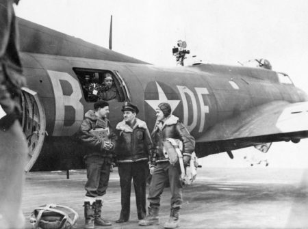 William Wyler (center) talking to some of the film crew members. The B-17 was specially modified to accommodate high altitude filming. Photo by anonymous (c. 1943). 