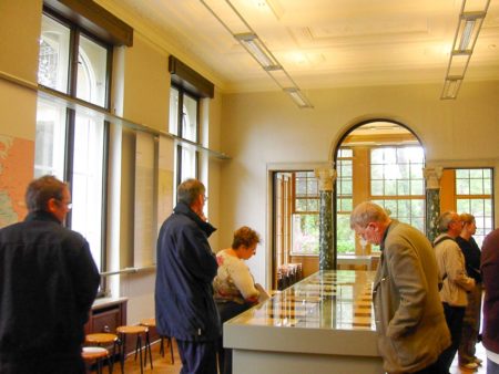 Conference room inside the Wannsee villa where the 90-minute meeting took place. Visitors are reviewing Eichmann’s minutes of the meeting. Photo by Adam Carr (May 2006). PD-Author release. Wikimedia Commons 