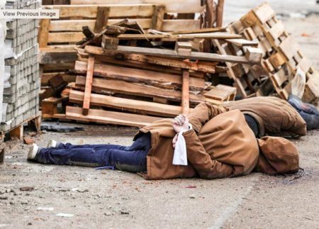 The body of a man, with his wrists tied behind his back, lies on a street in Bucha, Ukraine. Photo by Ronaldo Schemidt, AFP (c. April 2022). Getty Images.