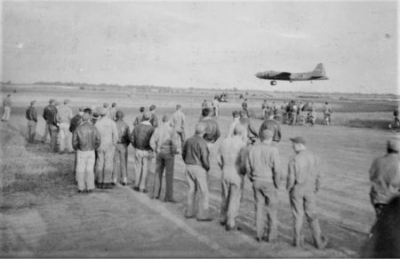 Ground crew watching a B-17 return to RAF Chelveston field after a mission. Photo by anonymous (c. 1943).