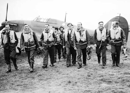 A group of pilots of No. 303 Polish Fighter Squadron walking away from a Hawker Hurricane after returning from a sortie. Photo by Stanley Arthur Devon (c. October 1940). Imperial War Museum. PD-U.K. public domain. Wikimedia Commons.
