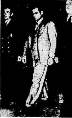 Herbert Karl Friedrich Bahr handcuffed to two deputy marshals as they leave the Federal Building at Newark (N.J.). He has just pleaded innocent to the charge of conspiracy to commit espionage. Photo by anonymous (date unknown). 