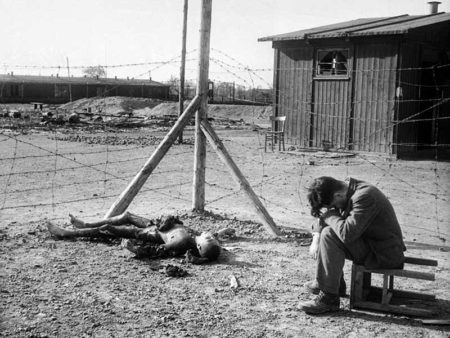 A young man sits next to a burnt body inside one of KZ Buchenwald’s sub-camps outside Leipzig, Germany soon after its liberation. 