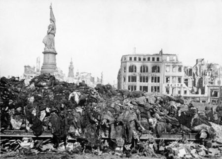 The aftermath of Allied carpet bombing of Dresden, Germany. Victims’ corpses are piled high with the ruins of bombed buildings in the background. 