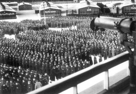 Roll call at KZ Sachsenhausen. Note the machine gun (upper right). Photo by anonymous (c. February 1941). Bundesarchiv Bild 183-78612-0003/CC-BY-SA 3.0. PD-CCA Share-alike 3.0 Germany. Wikimedia Commons.