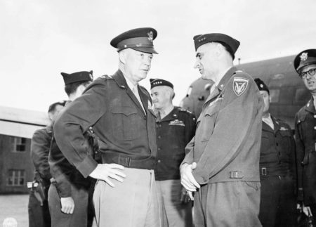 Gen. Dwight D. Eisenhower (left) in discussion with Gen. Lucius Clay (right) at Gatow Airport. Gen. Omar Bradley is in the background standing in the center background. Photo by anonymous (20 July 1945). U.S. National Archives and Records Administration. PD-U.S. government. Wikimedia Commons.