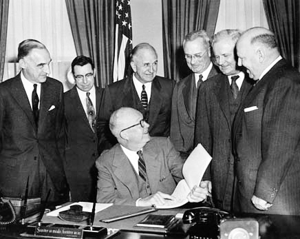 President Eisenhower receives a report from the President’s Advisory Committee on a National Highway System. Gen. Clay is on the far left. Photo by anonymous (11 January 1955). National Archives and the Dwight D. Eisenhower Presidential Library, Museum & Boyhood Home. PD-U.S. Government.