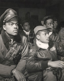 Members of the 332nd Fighter Group attending a briefing in Ramitelli, Italy. In the front are Robert W. Williams (left) and Ronald W. Reeves (right). Photo by Toni Frissell (c. March 1945). Library of Congress Prints and Photographs Division. PD-No known copyright restrictions. Wikimedia Commons.