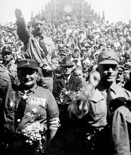 Hitler (standing left) and Göring (standing left forefront) during a NSDAP rally in Nuremberg. Photo likely by Heinrich Hoffmann (c. August 1929). U.S. National Archives and Records Administration, Heinrich Hoffmann Collection. PD-Hoffmann photos are not copyrighted. Wikimedia Commons.