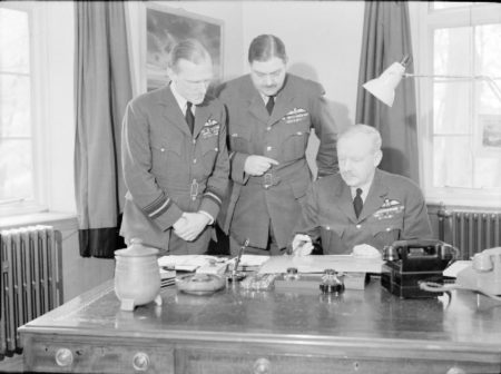 Royal Air Force Bomber Command senior officers. Air Chief Marshal Sir Arthur Harris is seated with his two senior staff officers, Air Vice-Marshall R. Graham (left) and Air Vice-Marshall R.R.M.S. Saundby (right). Photo by Mr. H. Hensser (c. 1943-1945). Air Ministry Second World War Official Collection. PD-Photo taken prior to 1 June 1957. Wikimedia Commons.