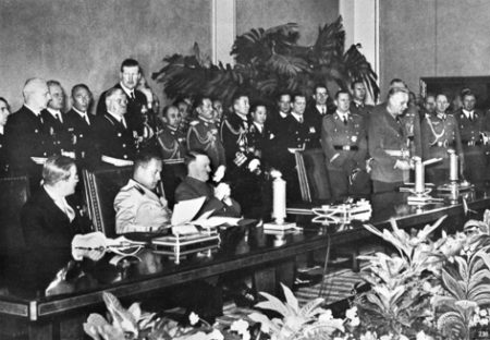 Signing ceremony for the Axis Powers Tripartite Pact. Seated from left to right: Japan Ambassador Saburō Kurusu, Italian Minister of Foreign Affairs Galeazzo Ciano, and Adolf Hitler. Joachim von Ribbontrop is speaking at the podium. Photo by Heinrich Hoffmann (27 September 1940). U.S. National Archives. PD-U.S. Government. Wikimedia Commons.