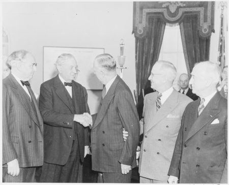 Gen. George C. Marshall shaking hands with Sen. Tom Connally of Texas, as Sen. Arthur Vandenberg of Michigan (far left), President Truman, and James Byrnes (far right) look on, after Marshall’s swearing-in as secretary of state. Photo by Abbie Rowe (21 January 1947). National Archives and Records Administration. PD-U.S. government. Wikimedia Commons.