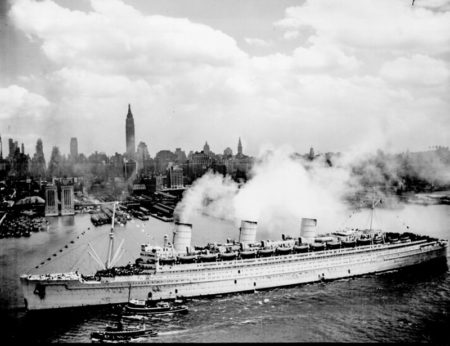 RMS Queen Mary sailing up the New York Harbor at the end of the war. Notice the troops standing on her decks. Photo by anonymous (c. June 1945). PD-U.S. government. Wikimedia Commons.